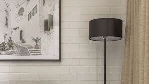 A room with a green sofa, a floor lamp, a small round table, and a framed picture on the wall. - Main Beach Apartments (Byron Bay)