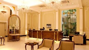 Un vestíbulo de hotel con una recepción, zona de estar y un espejo grande.