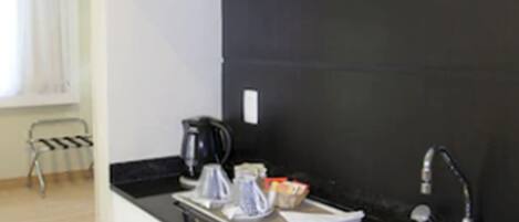 A modern kitchen with a black countertop, stainless steel sink, and a microwave.