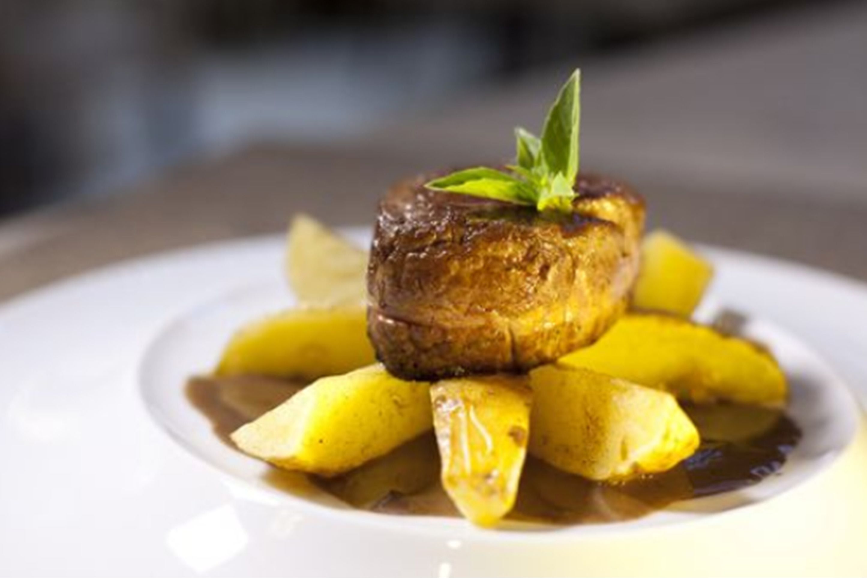 A plated dish with a steak and potatoes.