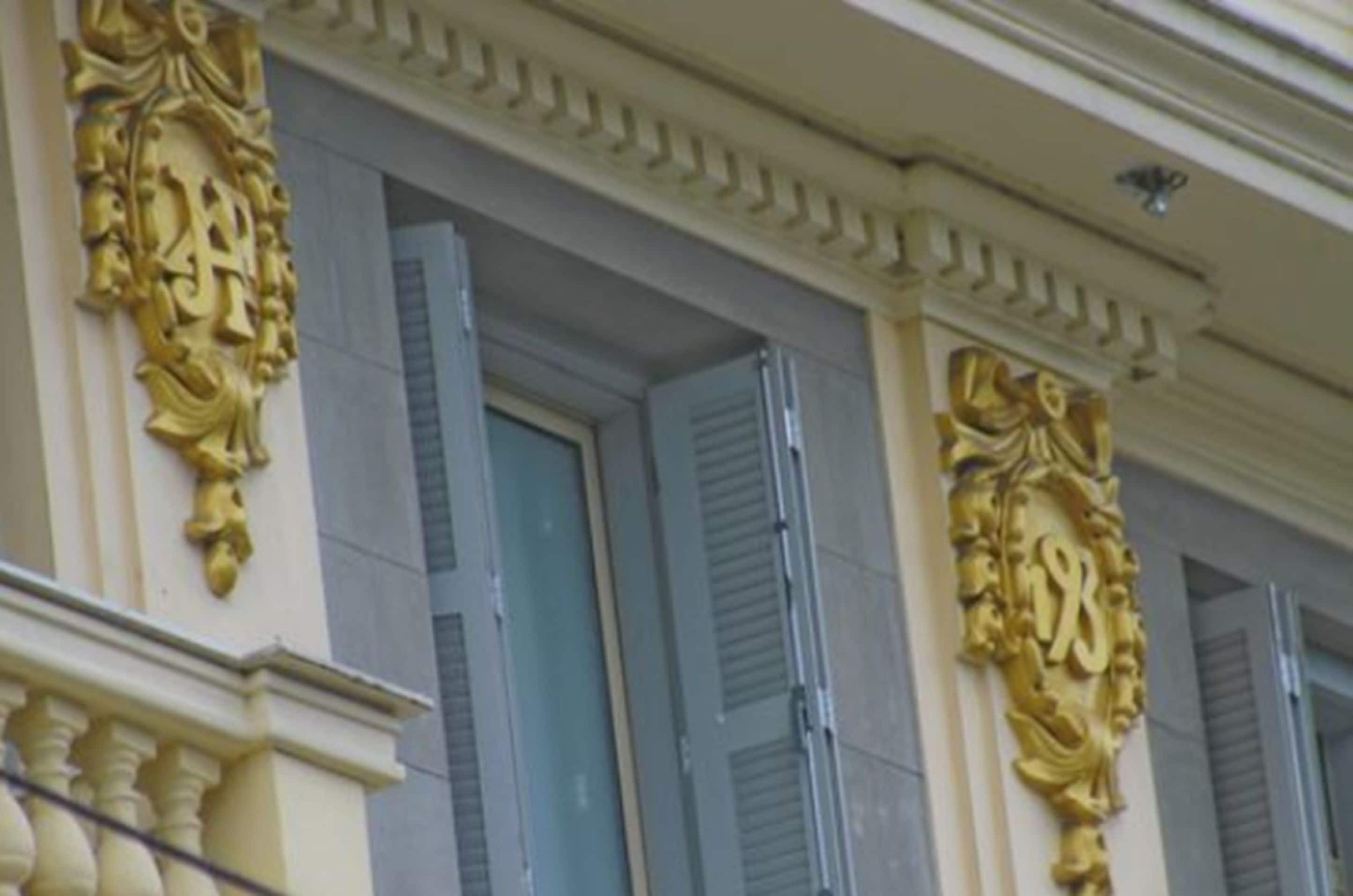 A building facade with ornate gold detailing and shutters.