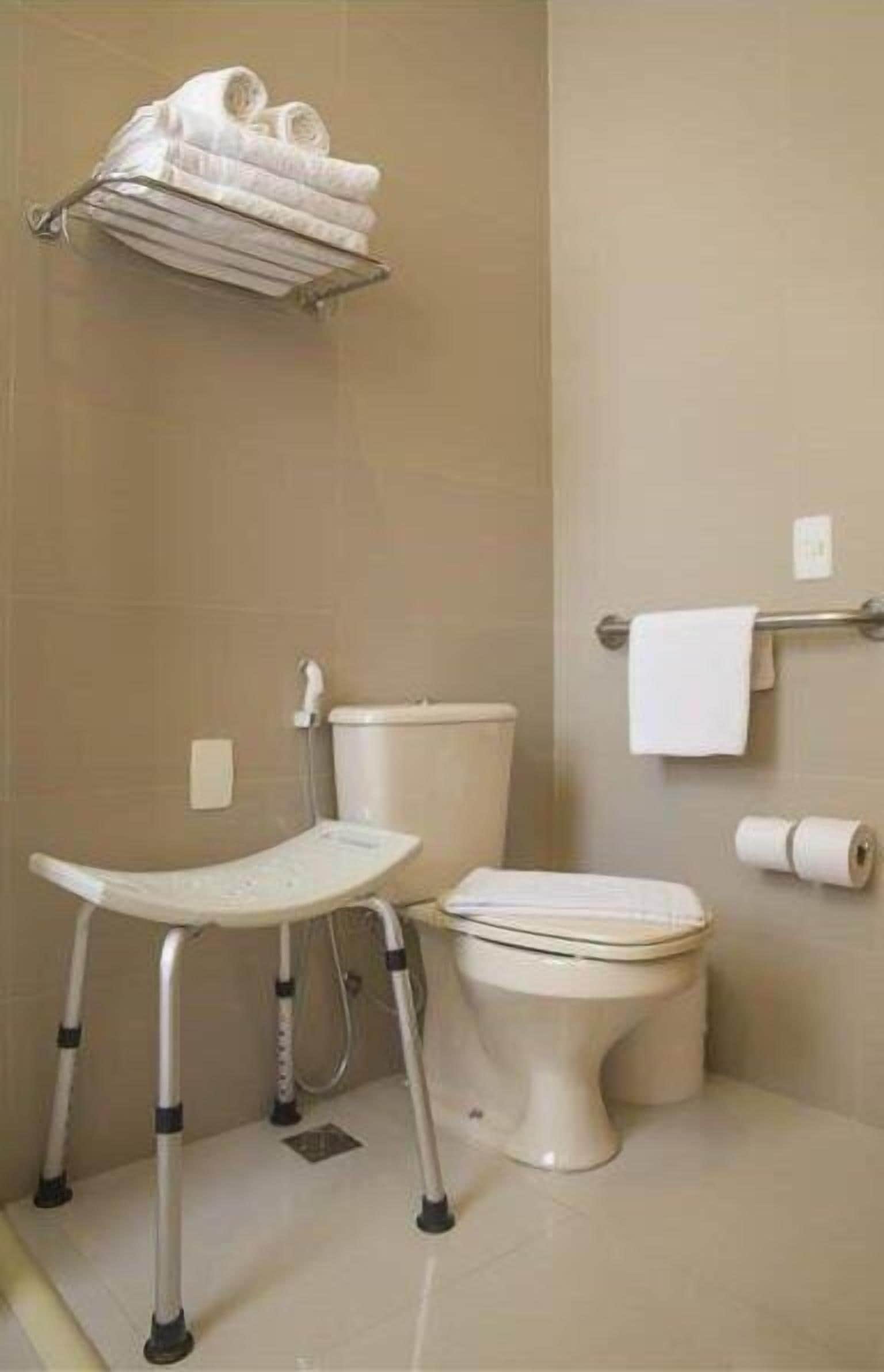 A bathroom with a toilet, a bidet, and a wheelchair-accessible bench.