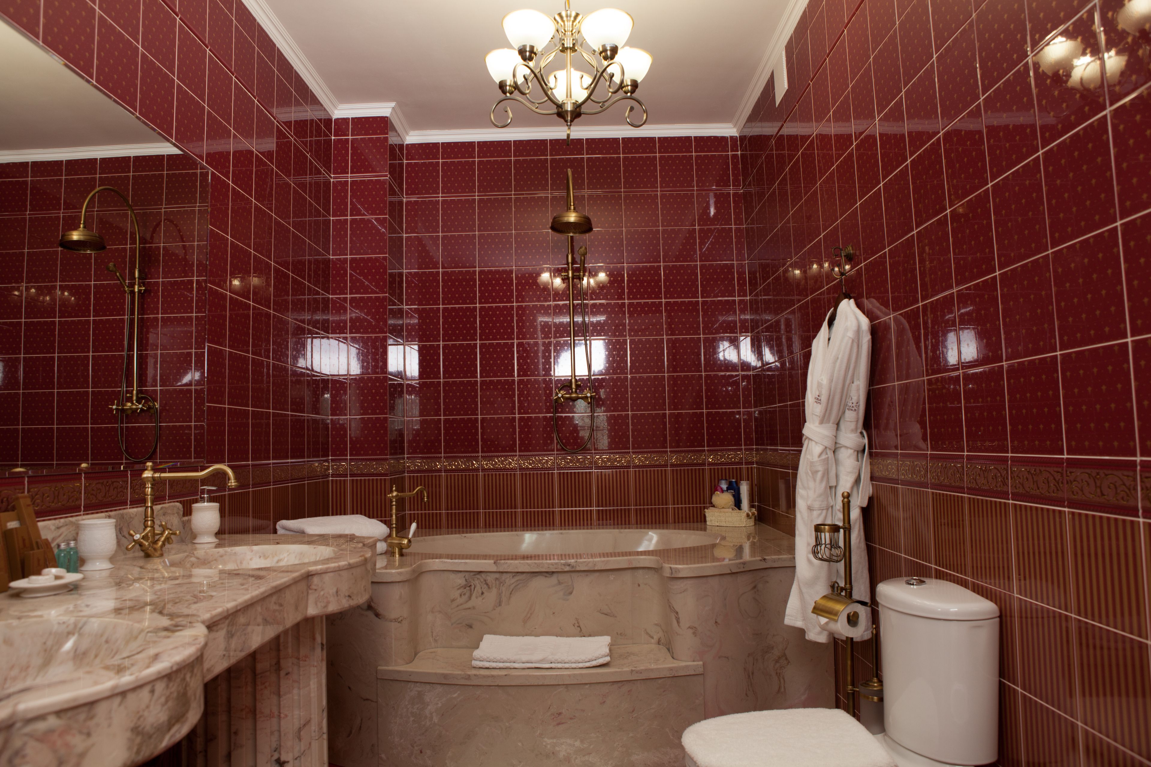 Un baño con tocador de mármol, bañera independiente, inodoro y ducha con grifo dorado.
