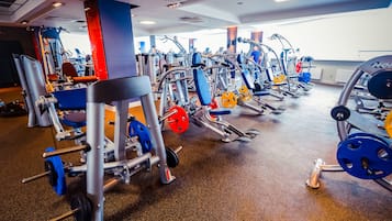 Une salle de sport équipée de divers appareils d’exercice, dotée d’un sol ciré et offrant un environnement lumineux et bien éclairé.