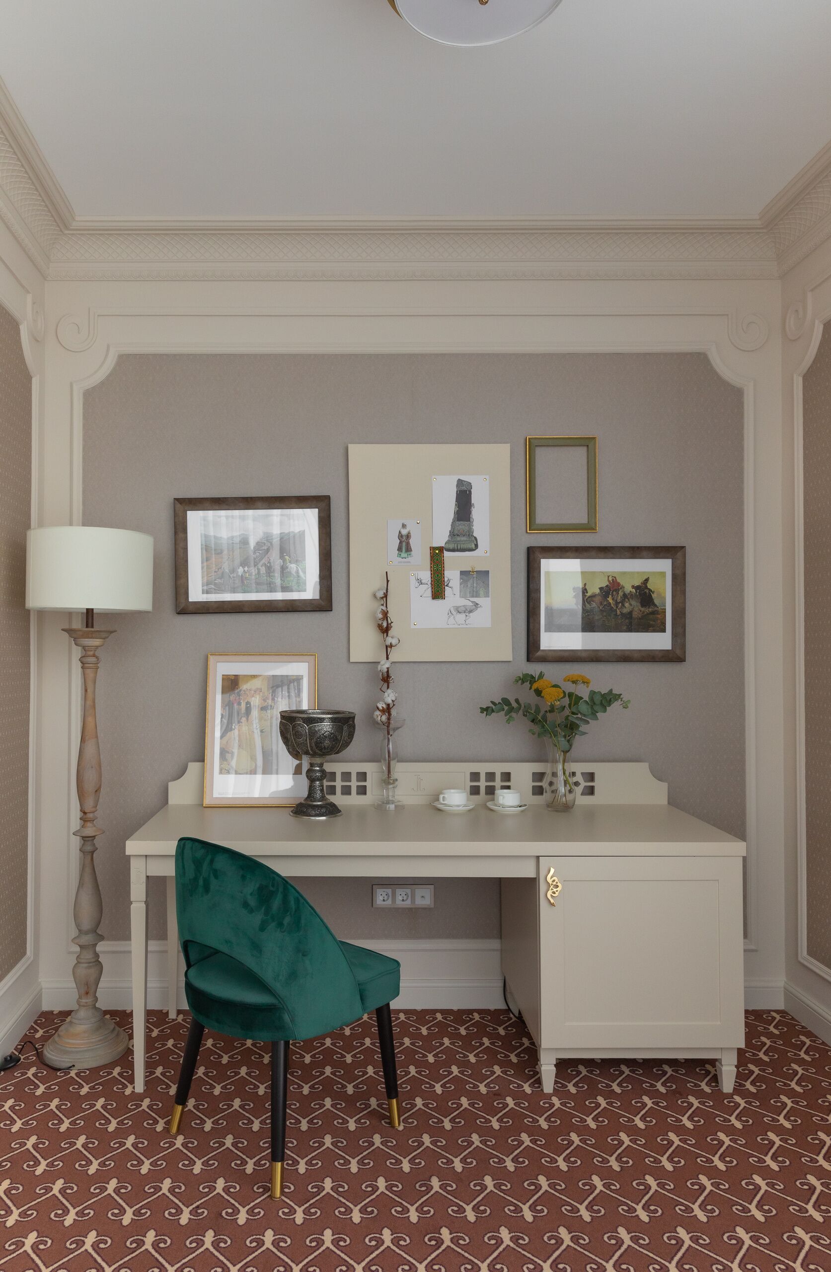 Un estudio con escritorio, silla e imágenes colgadas en la pared.
