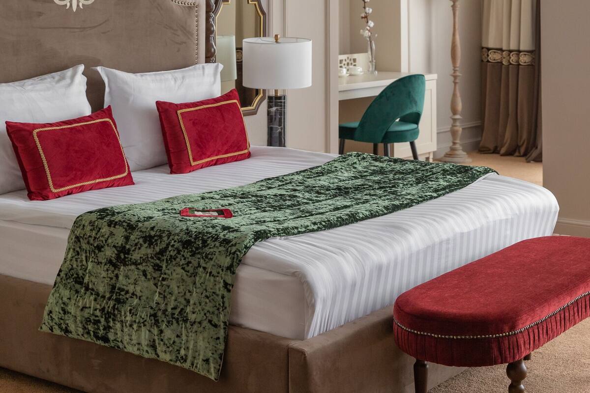 A hotel room with a large bed, a desk, a chair, and a lamp.
