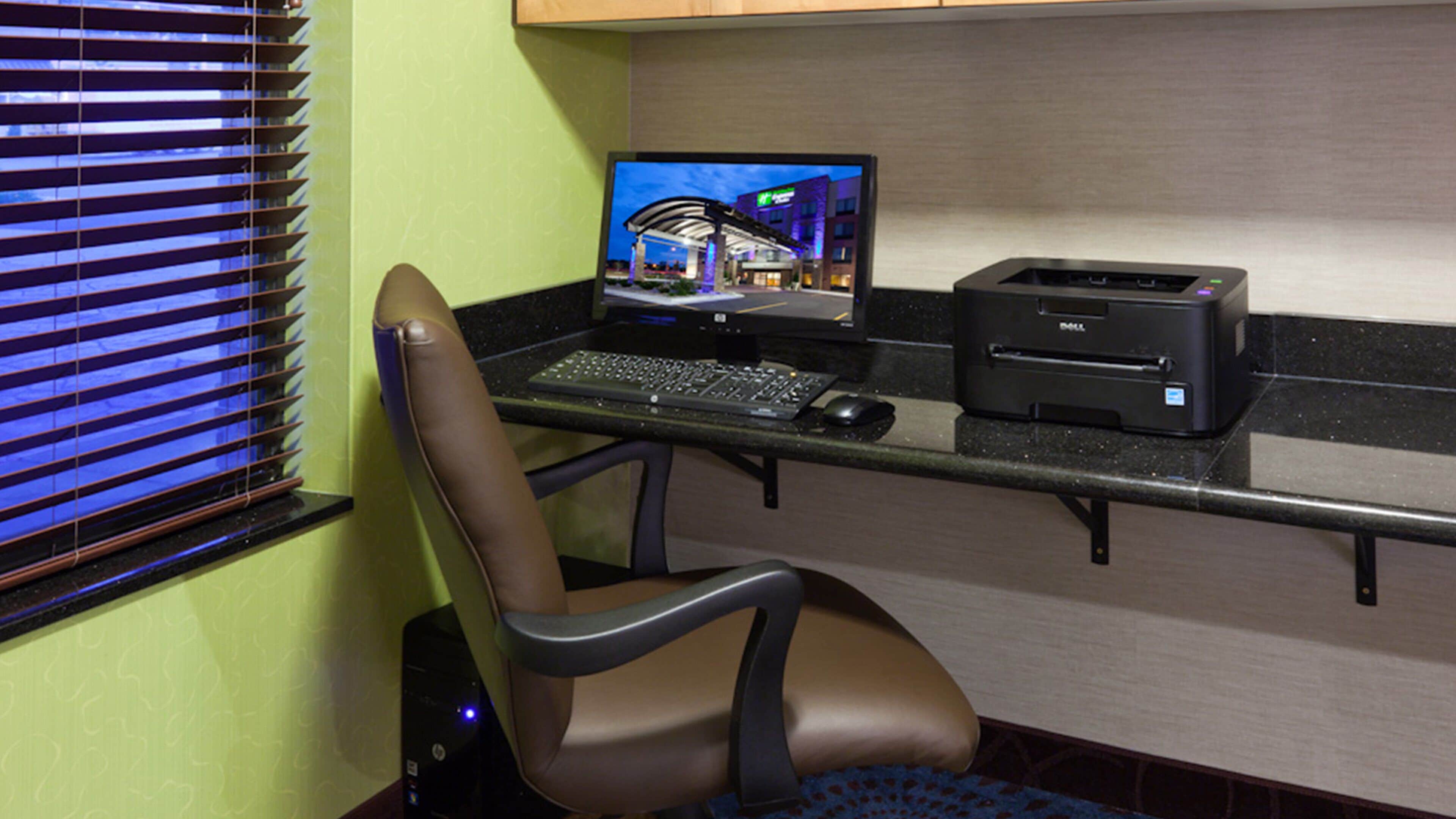 A home office setup with a laptop, keyboard, mouse, and printer on a desk.