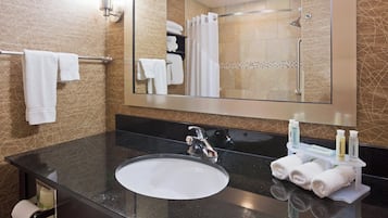 Casa de banho com lavatório, espelho, porta-toalhas e artigos de higiene pessoal.