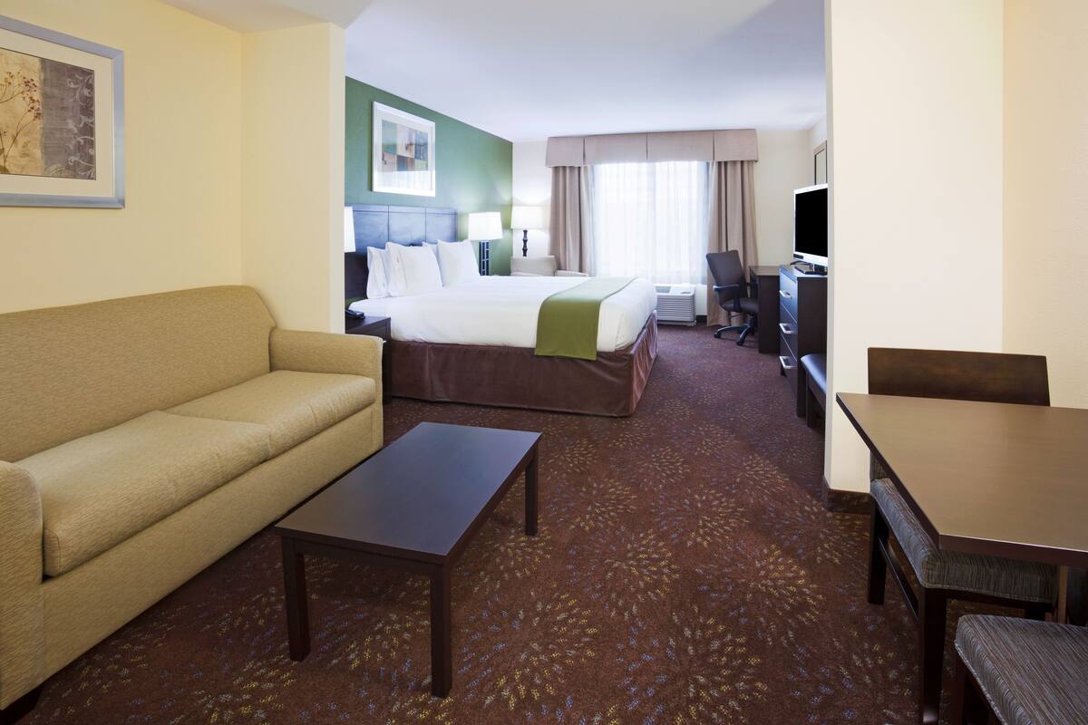 A hotel room with a bed, a sofa, a desk, and a television.