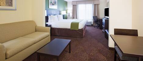 A hotel room with a bed, a sofa, a desk, and a television.