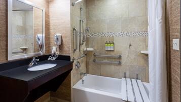 A modern bathroom with a sink, mirror, shower, and bathtub.