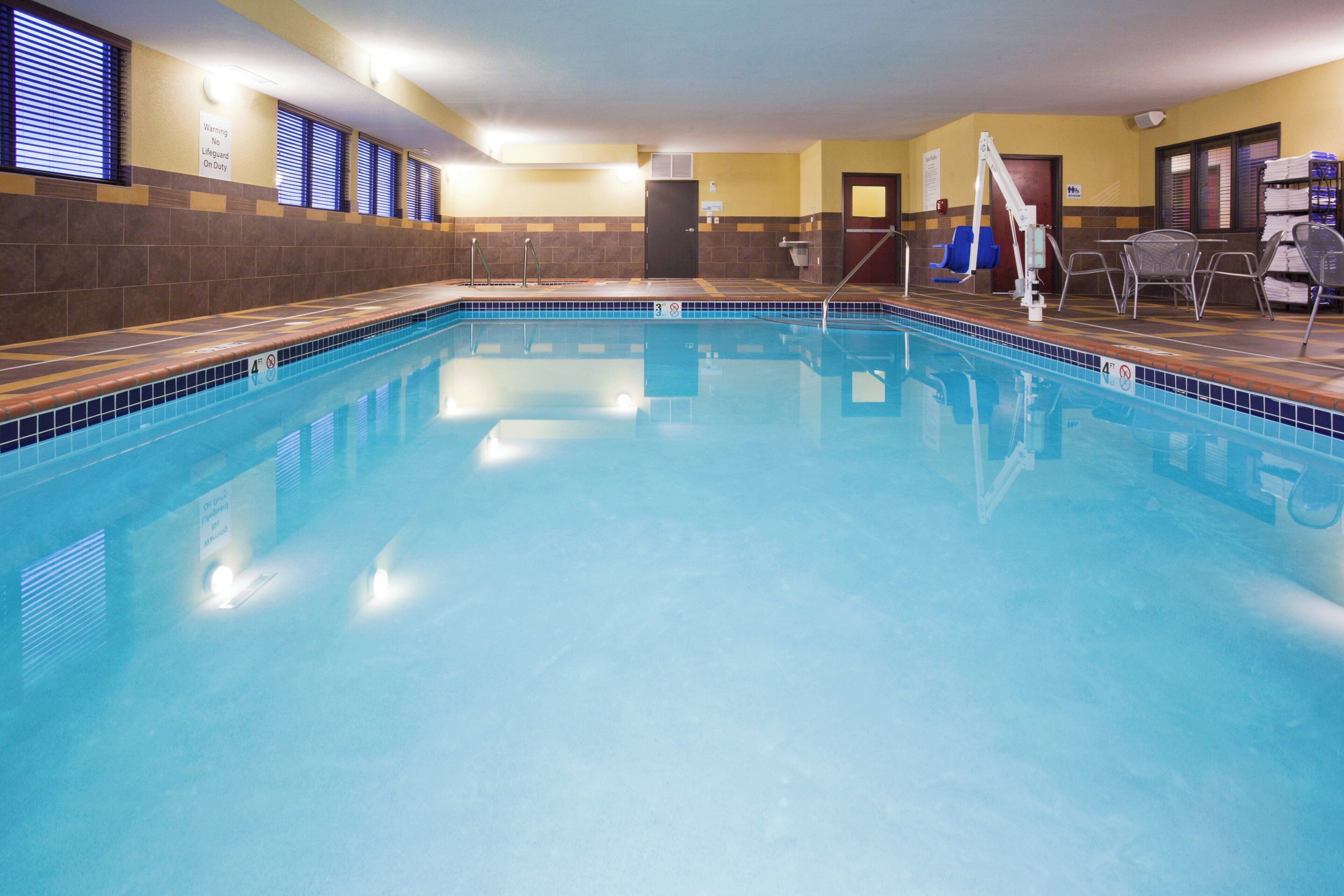 An indoor swimming pool with clear water, tiled walls, and a lifeguard station.