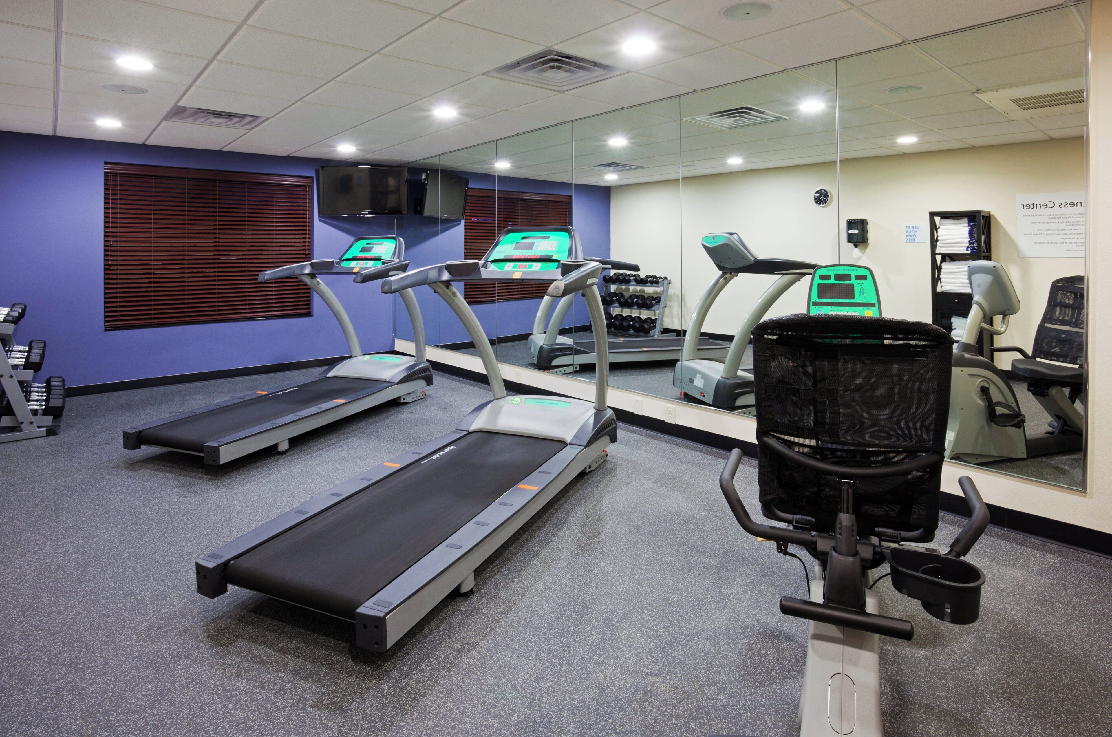 A gym with treadmills, a stationary bike, and a mirrored wall.