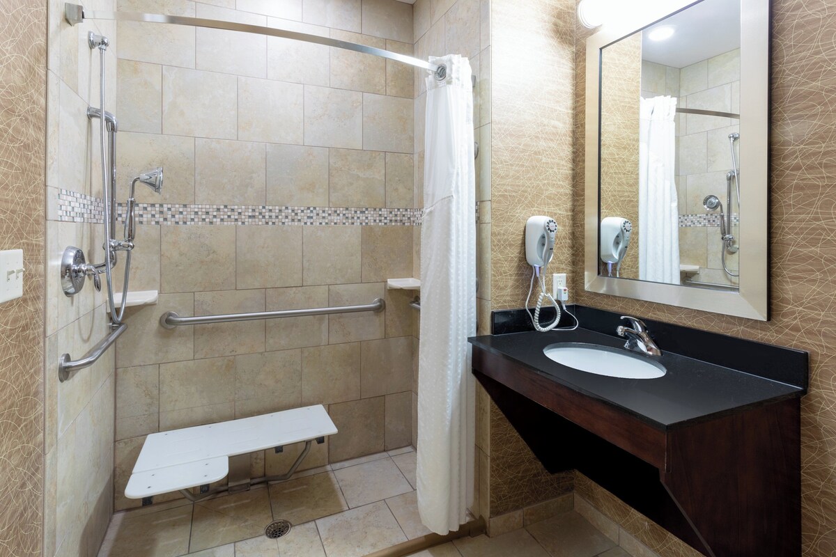 Une salle de bain équipée d’une douche, d’un lavabo, d’un miroir et d’un sèche-mains.
