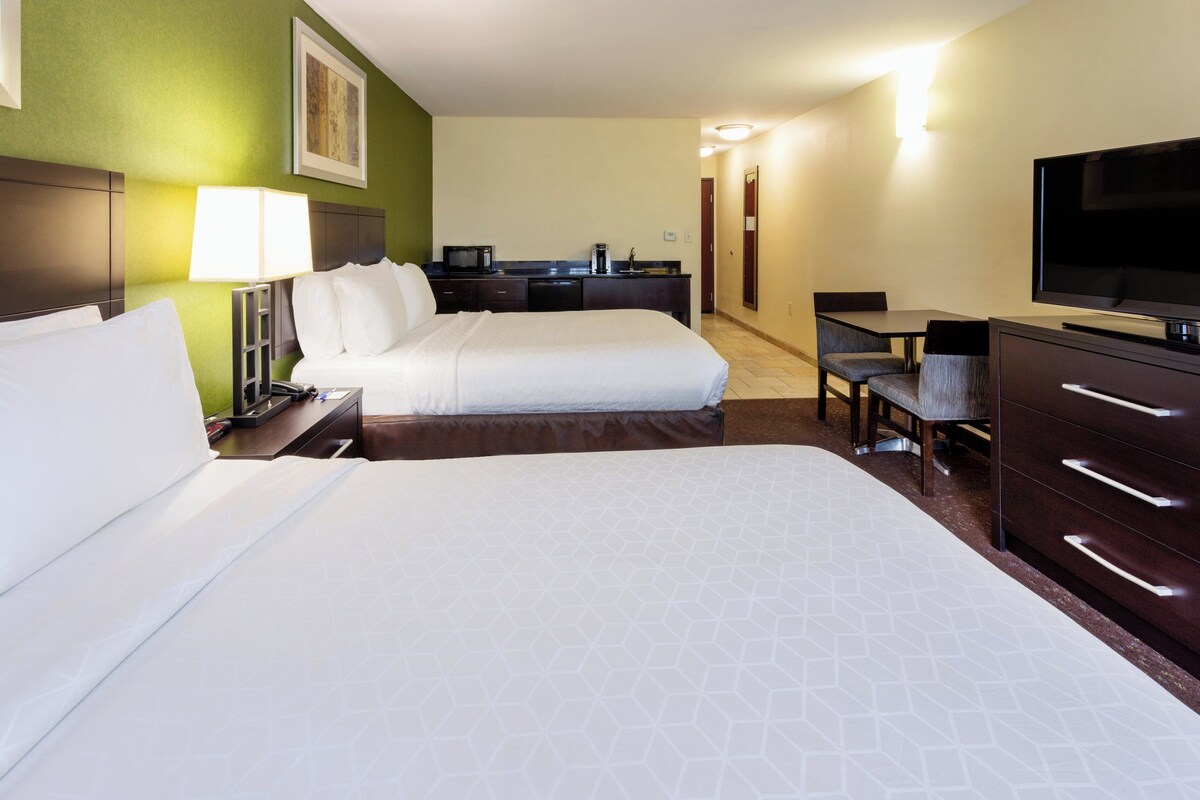Une chambre d’hôtel avec deux lits, un bureau, une télévision et une kitchenette.