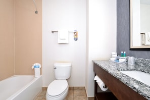A bathroom with a bathtub, toilet, and a vanity with a sink and mirror.