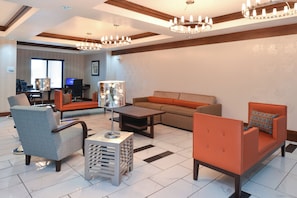 Un salón amplio con sofá, sillones, una mesa de centro y un televisor al fondo.
