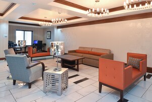 Un salón amplio con sofá, sillones, una mesa de centro y un televisor al fondo.
