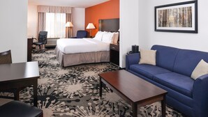 Une chambre d’hôtel avec un lit, un canapé bleu, une table basse en bois, un bureau et une chaise.