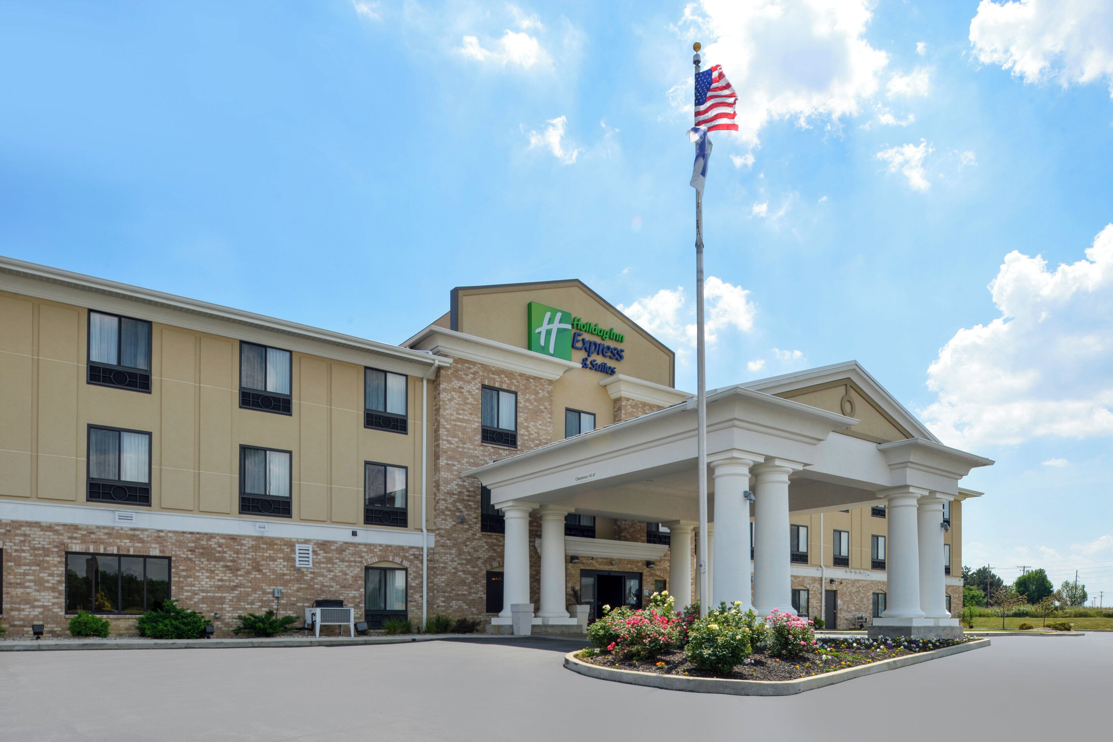 Un hôtel Holiday Inn Express & Suites doté d’une entrée couverte et d’un mât pour drapeau.