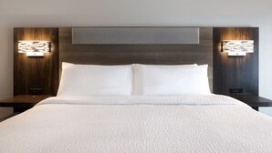 Ein Hotelzimmer mit einem großen Bett, zwei Nachttischen und Wandleuchten.