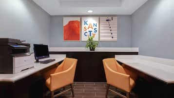 Um escritório moderno com uma mesa, duas cadeiras, uma impressora e obras de arte emolduradas na parede.