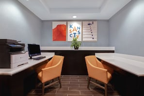 Um escritório moderno com uma mesa, duas cadeiras, uma impressora e obras de arte emolduradas na parede.