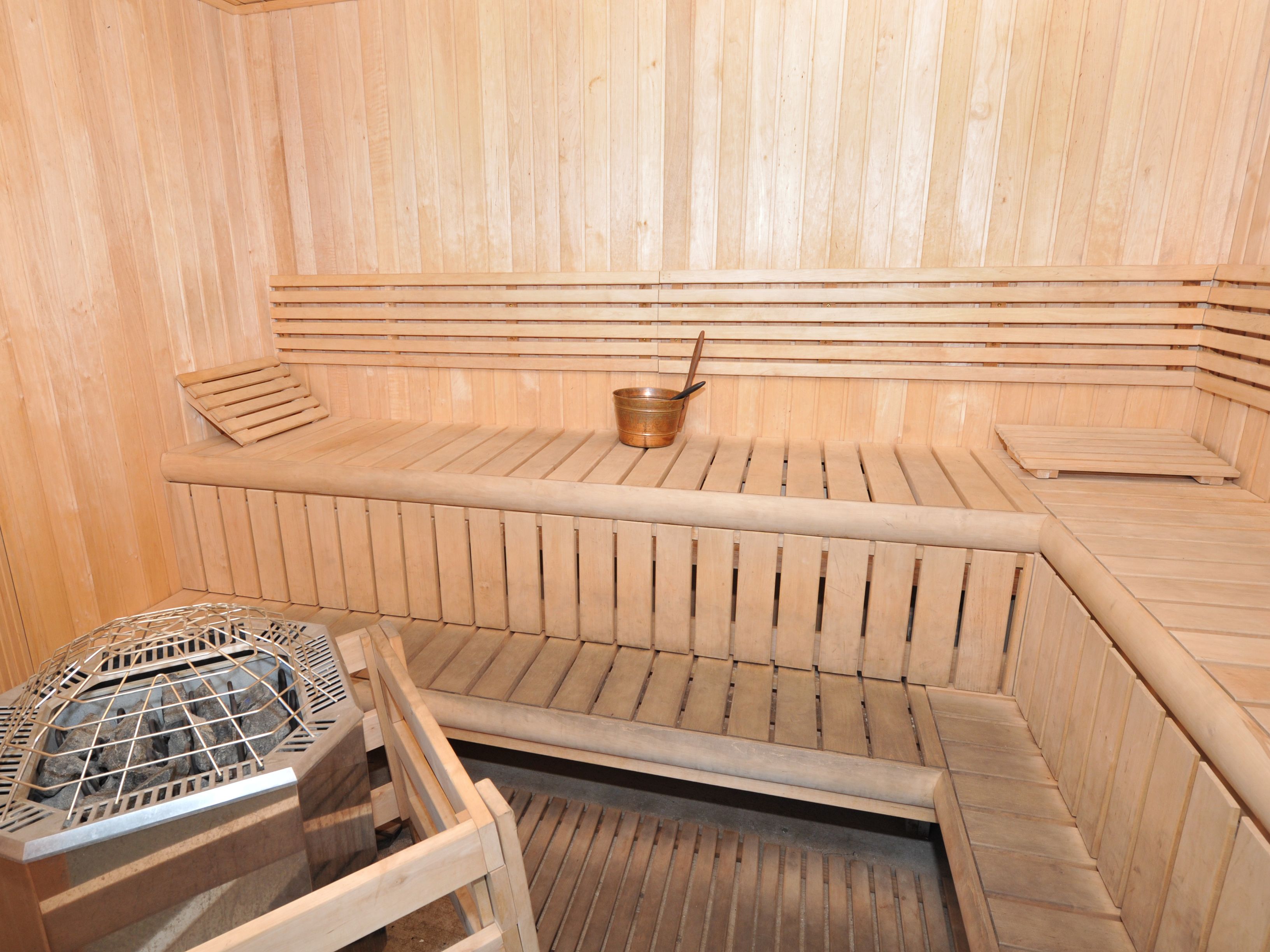 Een sauna met houten banken en een metalen verwarmingselement.