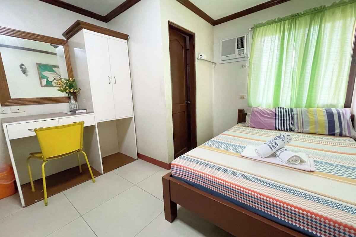 Une chambre à coucher comprenant un lit, un bureau, une chaise et une armoire.