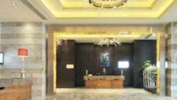 A lobby with a marble floor, a reception desk, a chandelier, and a framed artwork on the wall.