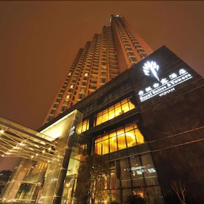 A high-rise building with illuminated windows and a prominent sign. - Royal Suites & Tower (Wuhan)