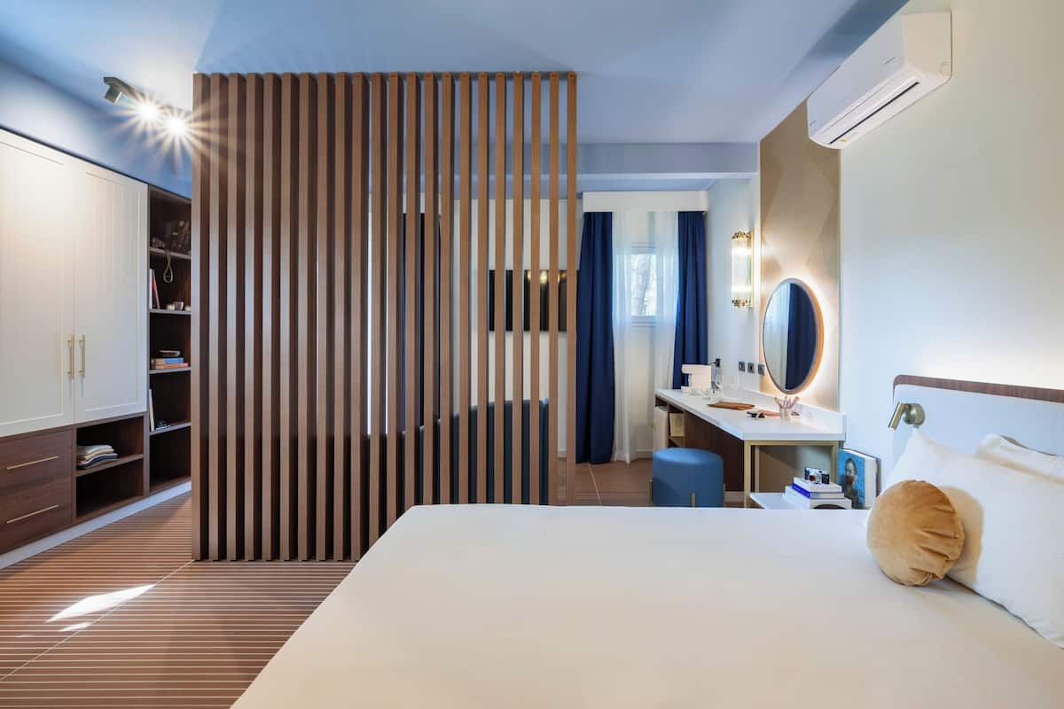 A modern hotel room with a large bed, a desk, a wardrobe, and a sliding partition.