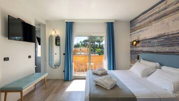 Una habitación de hotel moderna con cama, un banco, televisor y balcón con vistas al exterior.