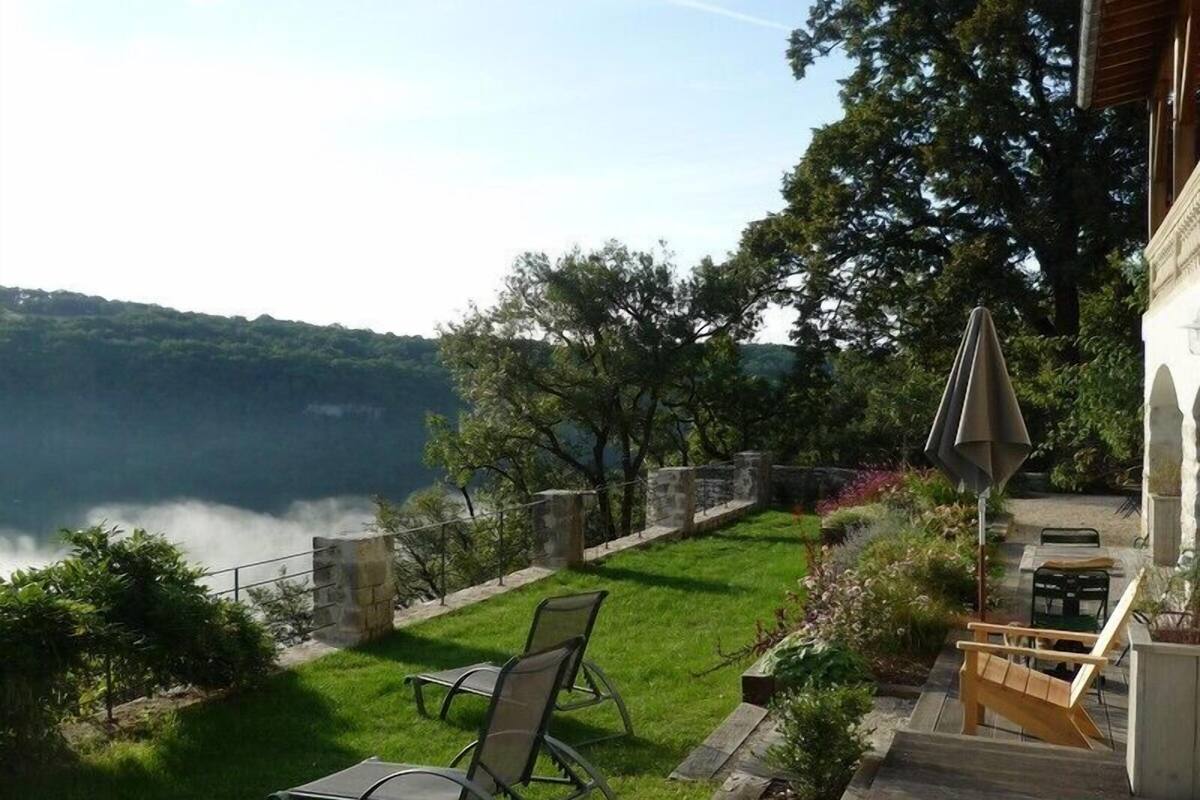 Un patio con dos sillas de jardín, una terraza de madera y vista a un lago.