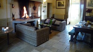 Una habitación acogedora con chimenea, muebles de mimbre y un comedor.