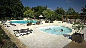 Un área de piscina con sillones de descanso y una pérgola de madera.