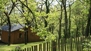Una cabaña de madera rodeada por una cerca de madera y árboles.