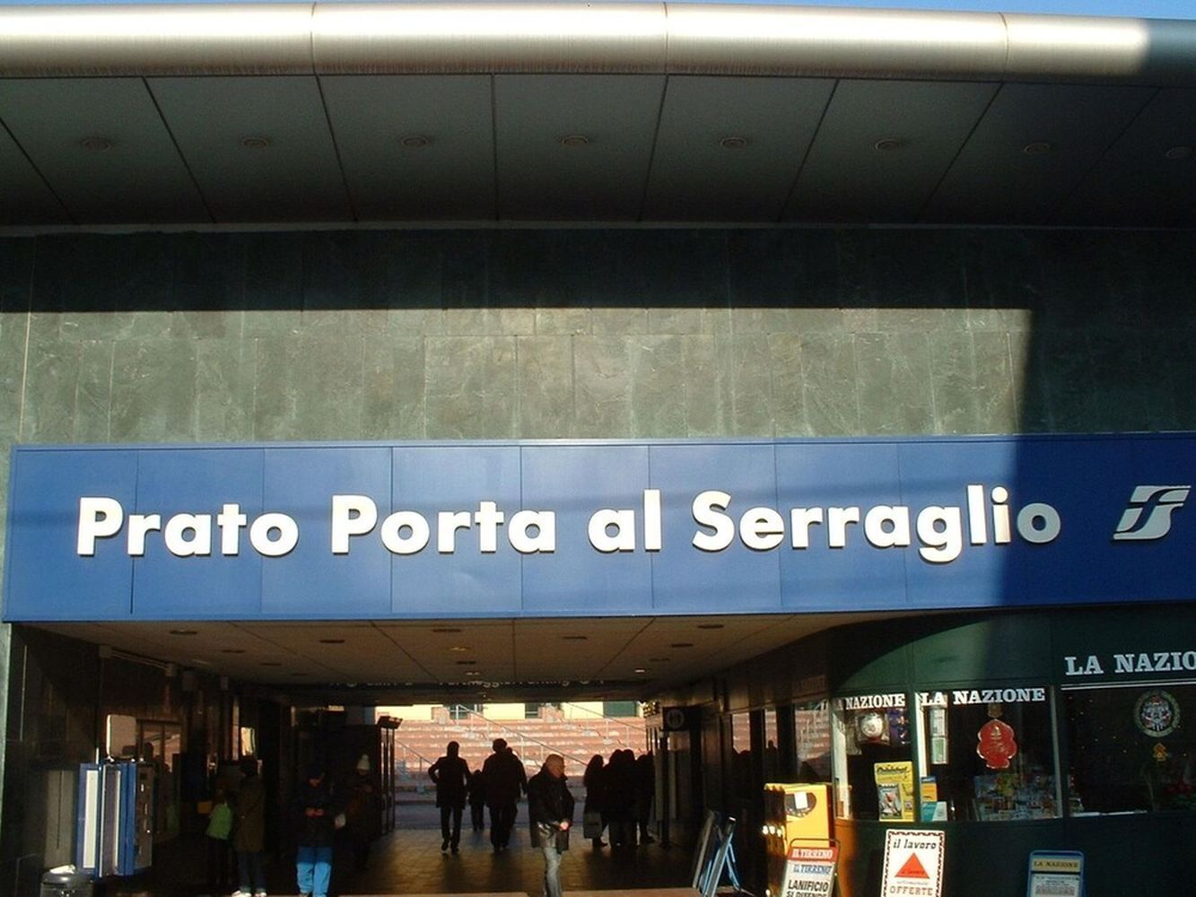 The entrance to Prato Porta al Serraglio with a sign above the door and a view of people entering.