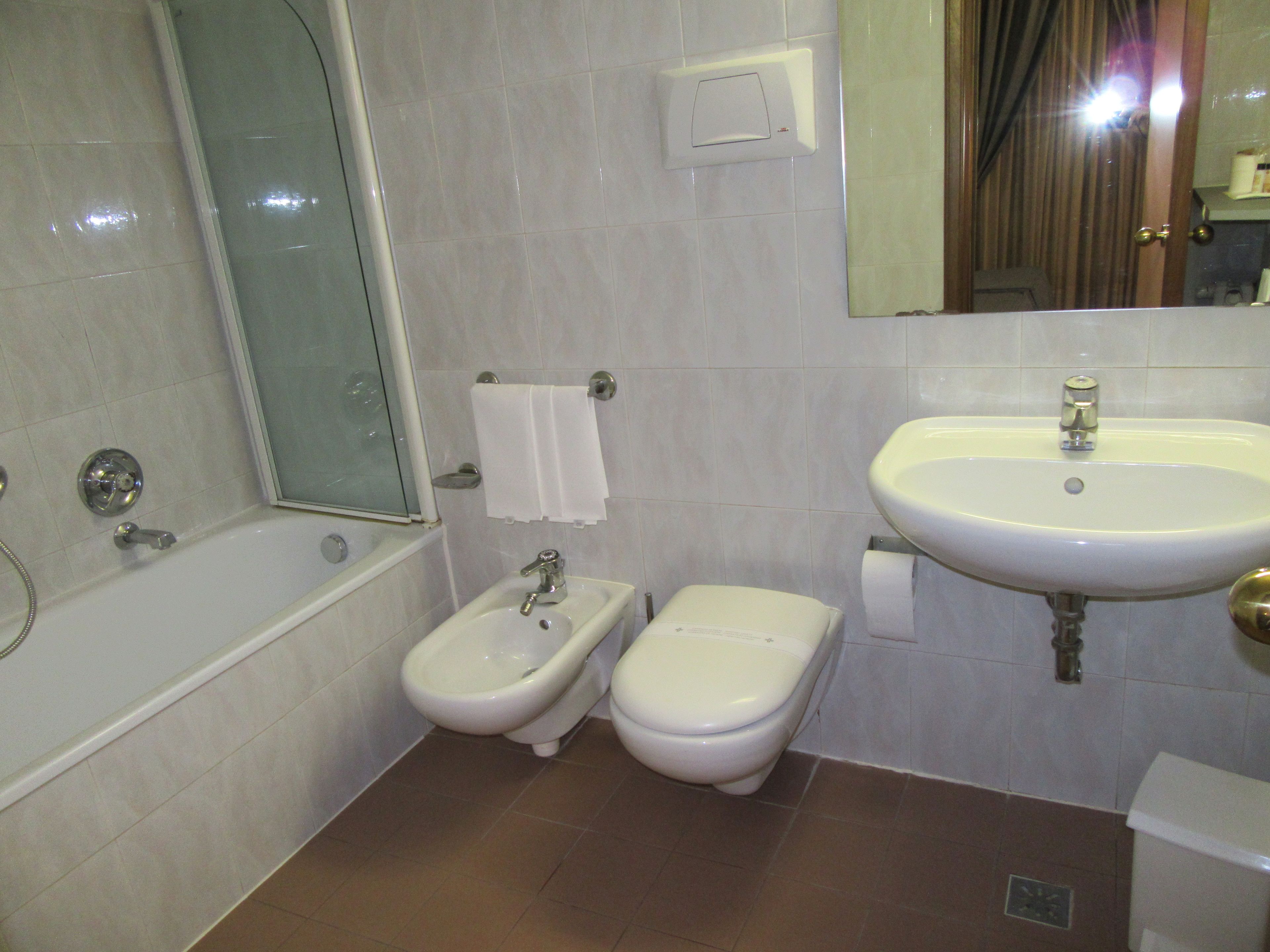 Un baño con bañera, bidé, lavabo y espejo.