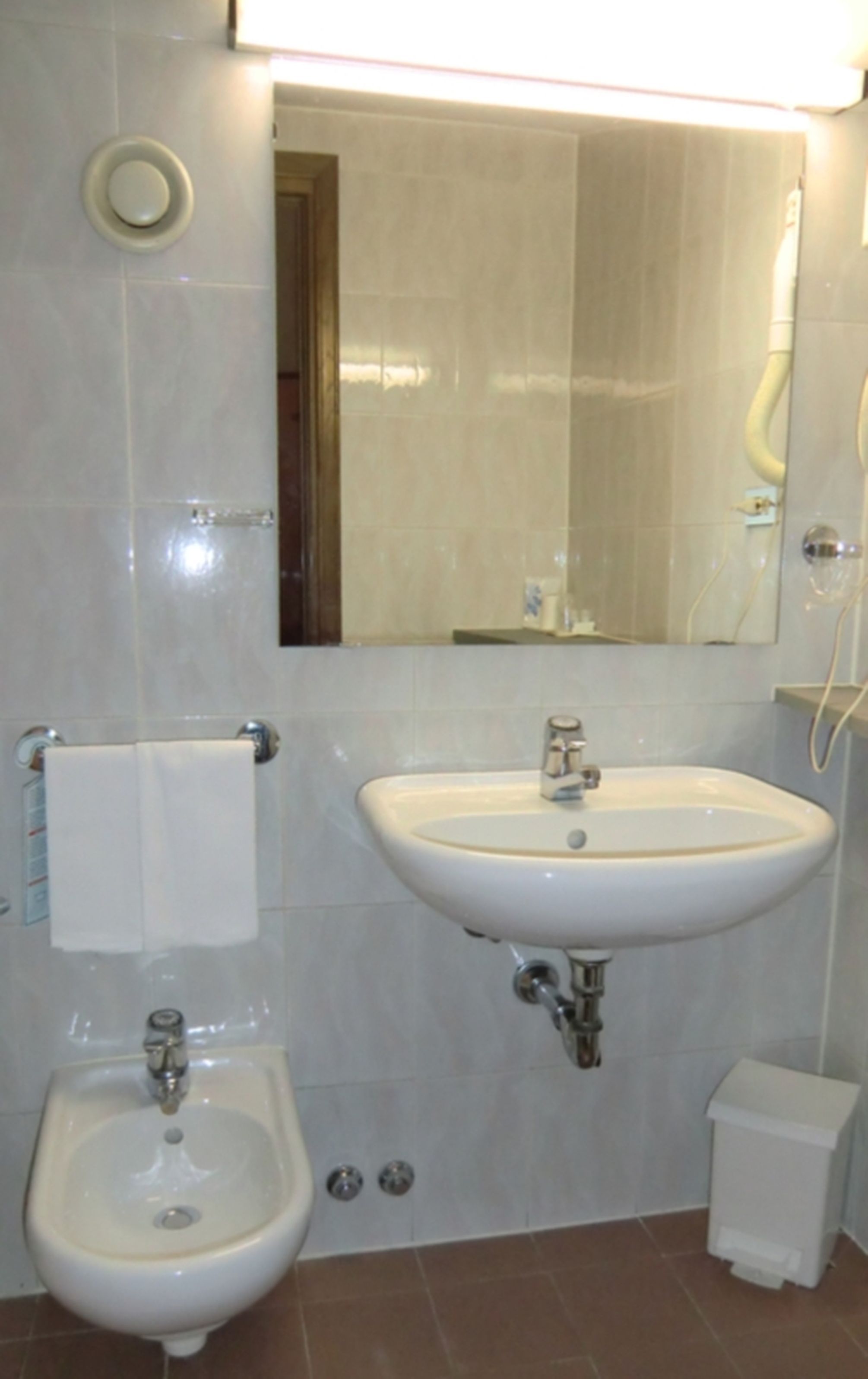 Un baño con bidé, lavamanos y espejo.
