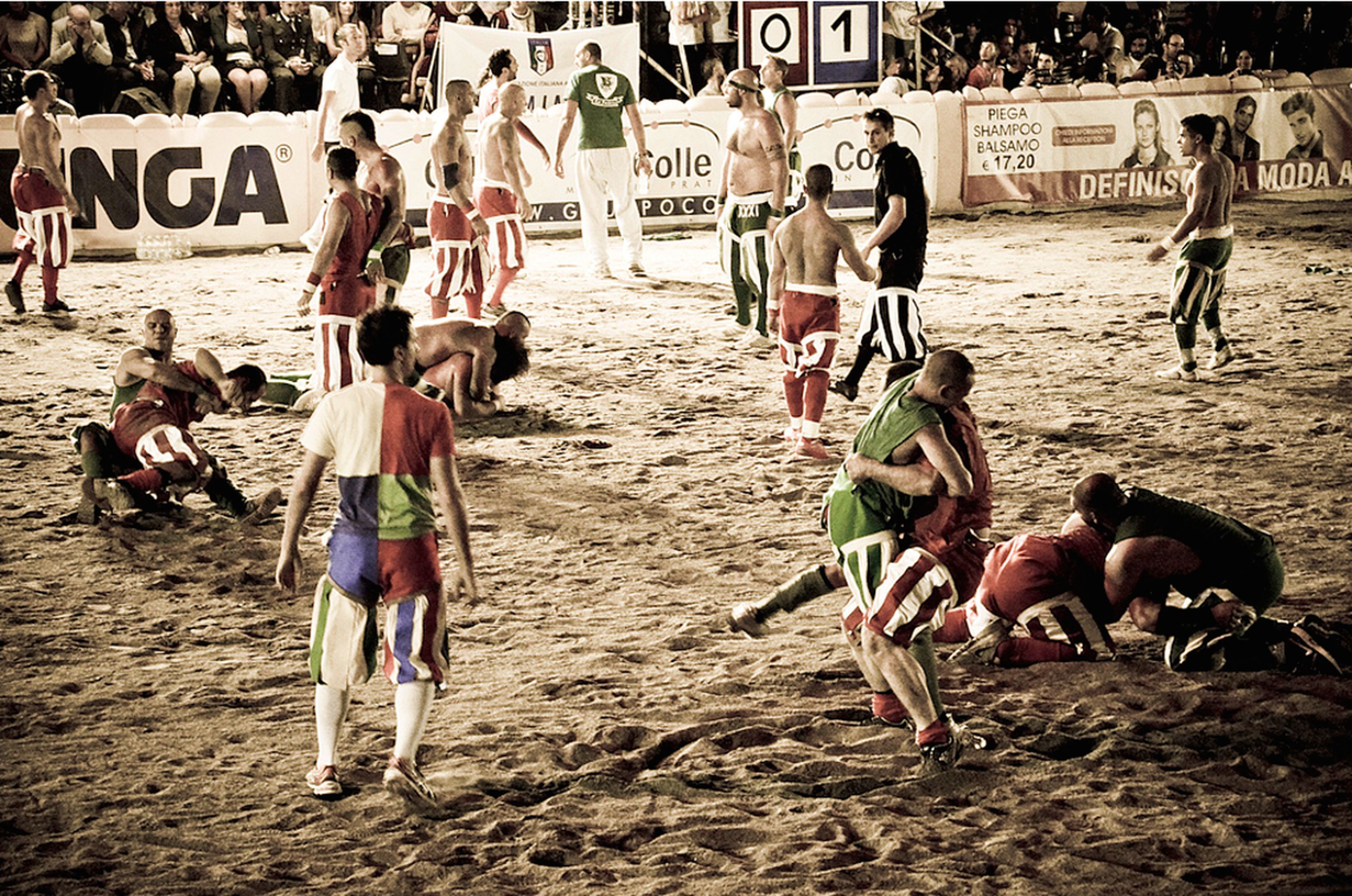 Egy homokos tengerpart, ahol emberek játszanak valamilyen sportot, valószínűleg strandfocit.