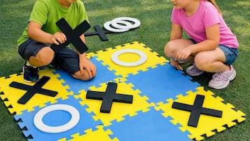 Zwei Kinder spielen draußen mit Puzzlespielmatten.