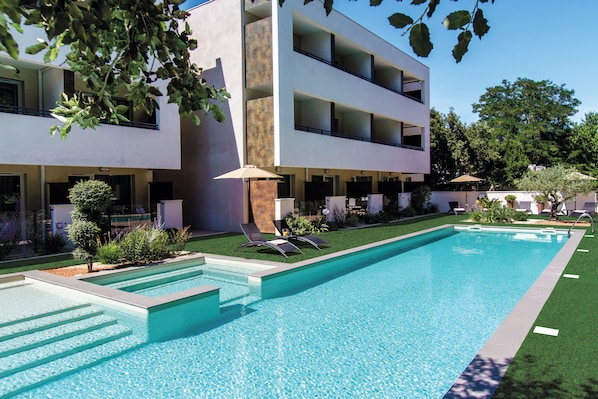 A modern hotel with a swimming pool, outdoor seating, and a well-maintained garden. - Forme Hotel & Spa Montpellier (Mauguio)