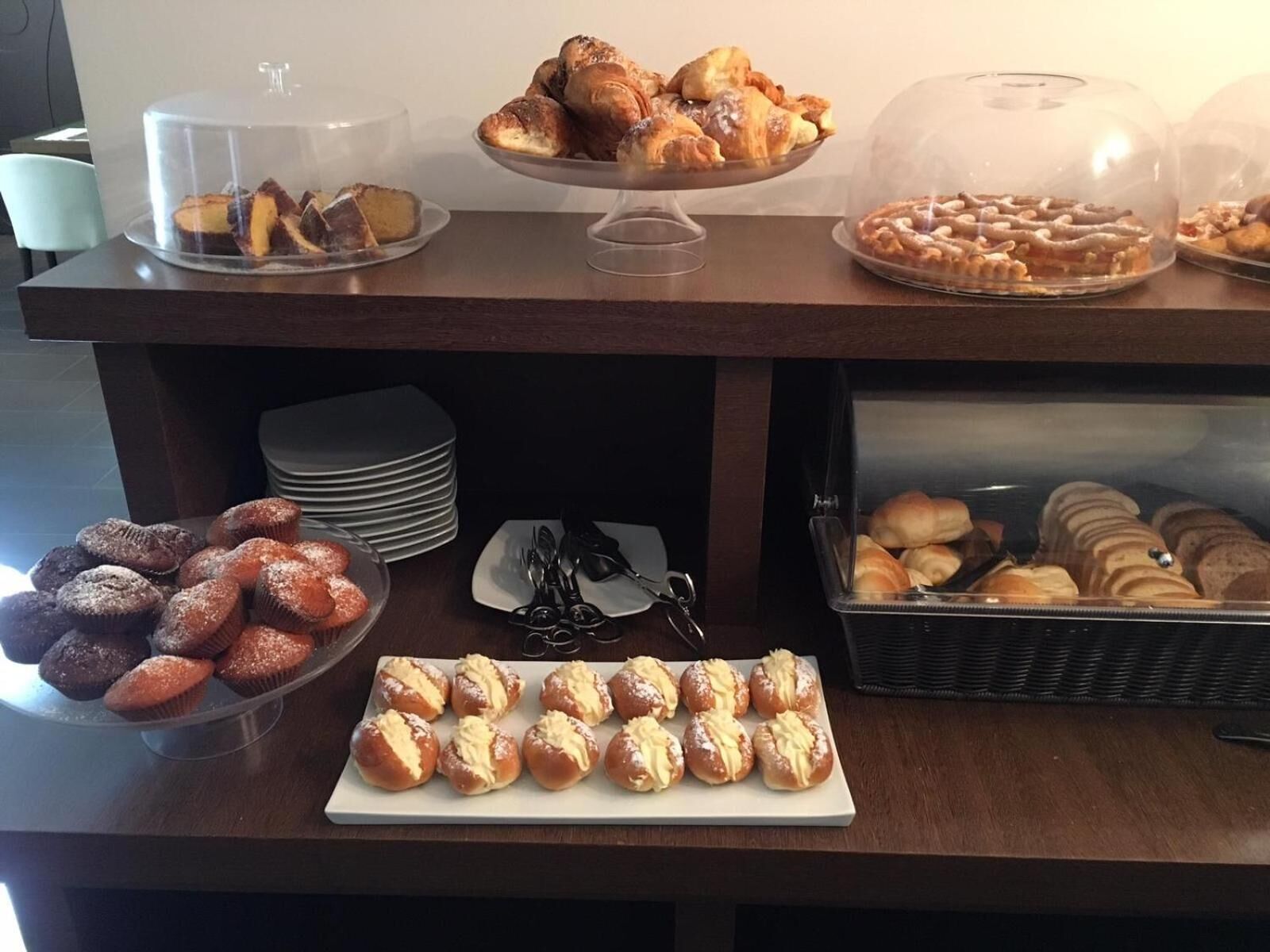 A buffet table with various baked goods, including muffins, pastries, and bread.