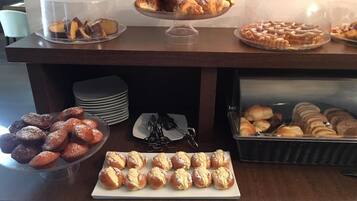 Ein Buffet mit verschiedenen Backwaren, darunter Muffins, Gebäck und Brot.