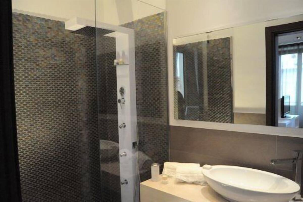 Een moderne badkamer met een douchecabine van glas, een wit wastafelmeubel en een grote spiegel.