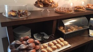 Een ontbijtbuffet met diverse gebakken producten, zoals muffins, gebak en brood.