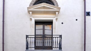 Een gebouw met twee verdiepingen, een balkon, een rondboogvormige ingang en een bord waarop staat dat het een hotel is.