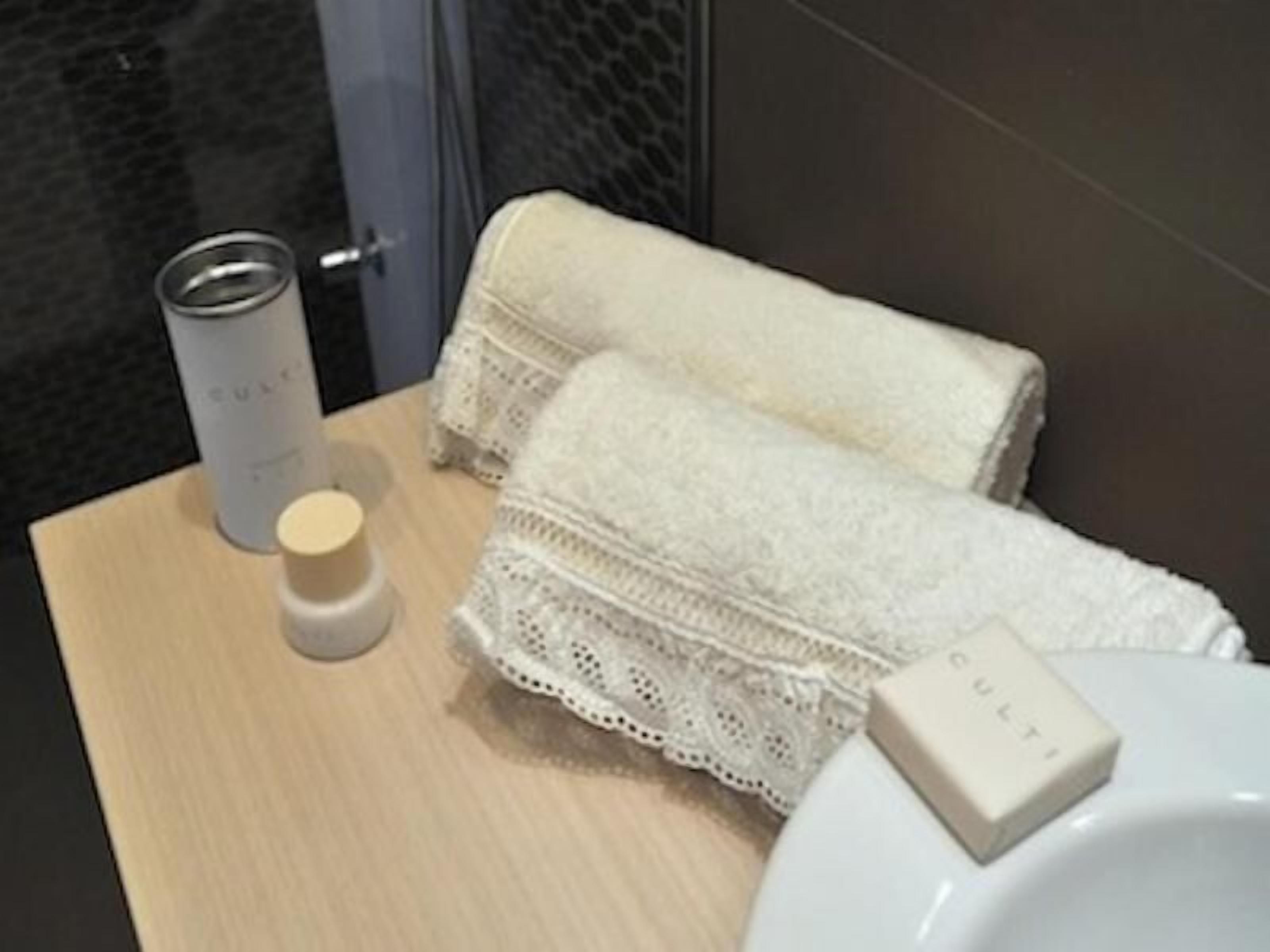 Une salle de bain avec un meuble-lavabo en bois, une serviette blanche, un flacon de lotion et un porte-savon.