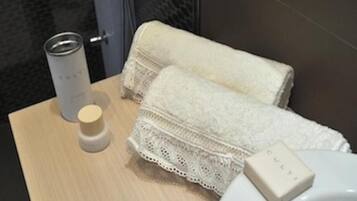 Une salle de bain avec un meuble-lavabo en bois, une serviette blanche, un flacon de lotion et un porte-savon.
